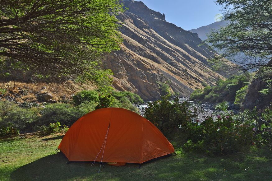 Оранжевая палатка в горах у реки