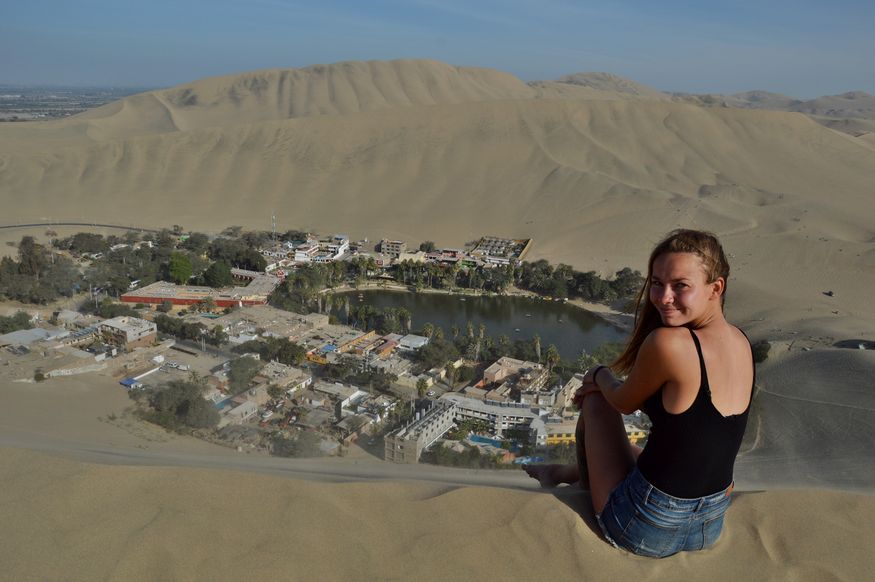 девушка сидит на дюне над оазисом Уакачина