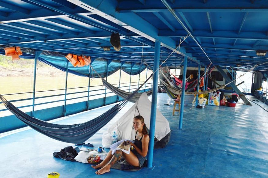 Девушка у гамака и палатки на палубе корабля в Амазонке
