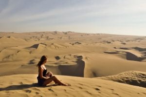 Девушка смотрит на желтую пустыню с высокой дюны