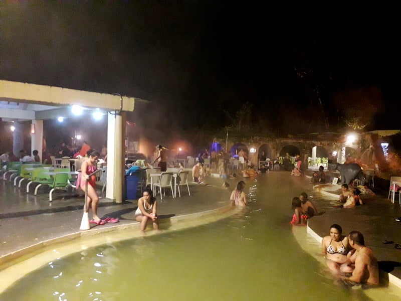 люди отдыхают вечером в бассейне около города Перейра