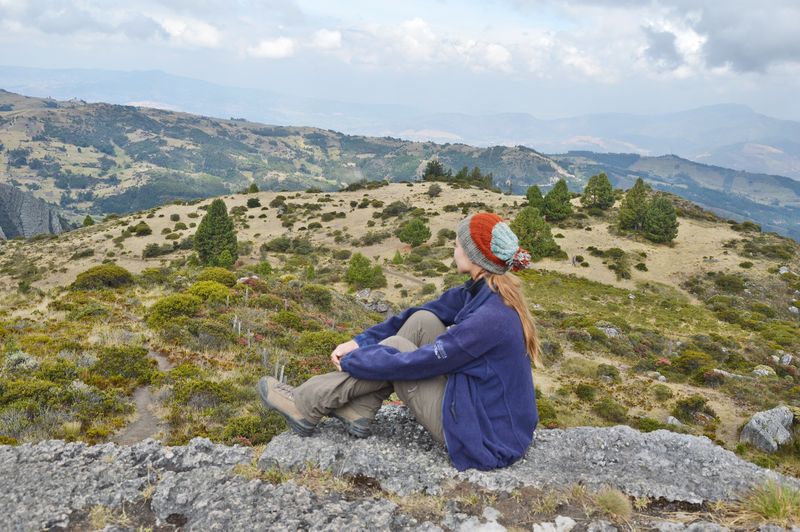 Девушка в шапке смотрит на долину сверху