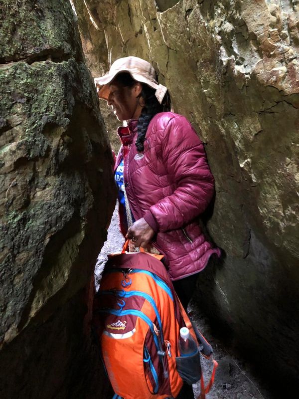 Женщина протискивается через узкий проход в скале