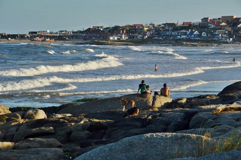 Люди сидят на камне с видом на пляж Пунта-дель-Дьябло в Уругвае