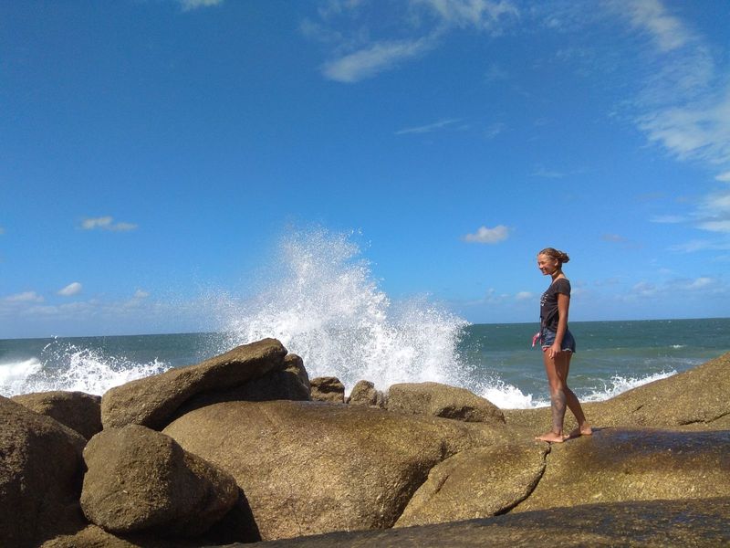 Девушка стоит на скале на фоне волн