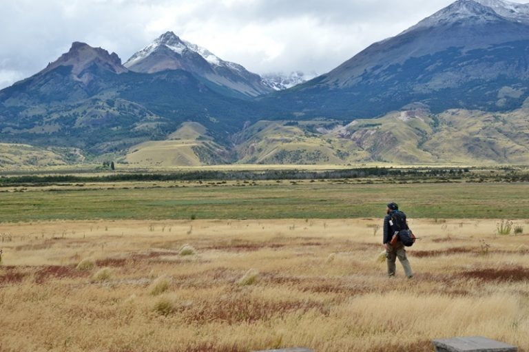 мужчина идет по полю на фоне гор — парк Патагония в Чили