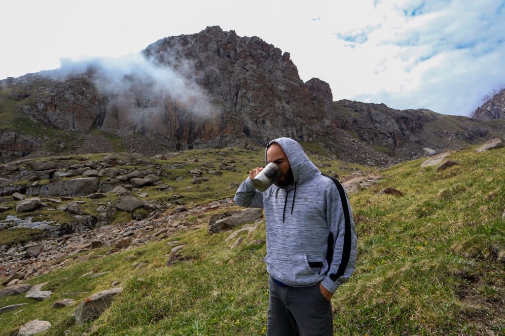 мужчина пьет воду в горах