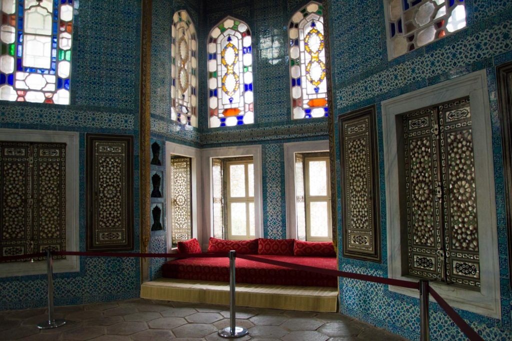 красный диван у окна и мозаика на стенах