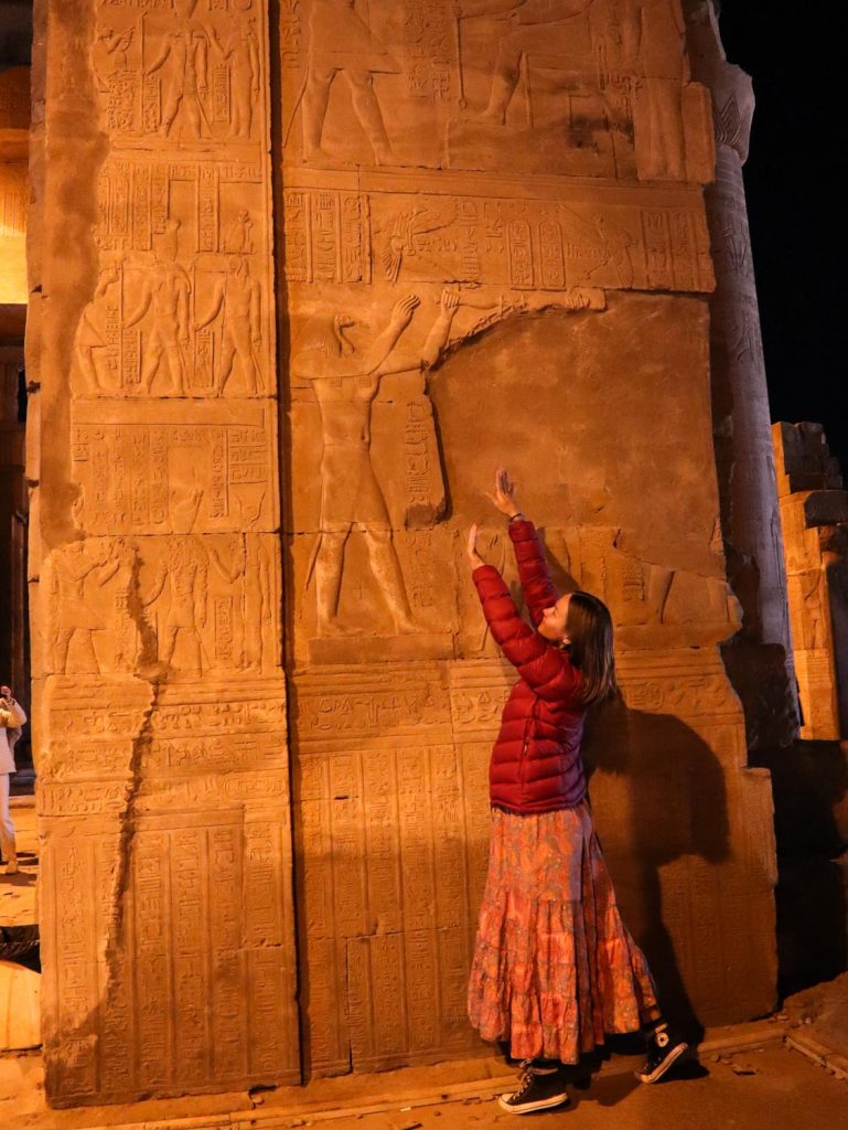 Туристка у стены с иероглифами в Египте