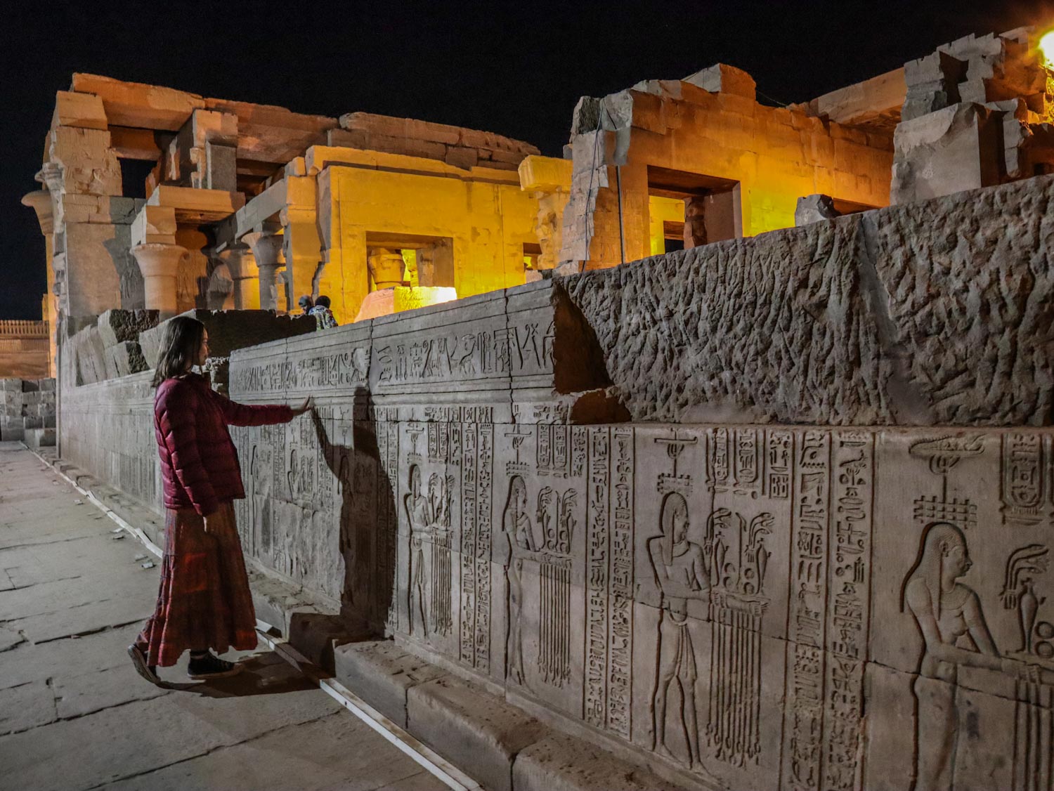 Девушка трогает стену храма в Египте ночью