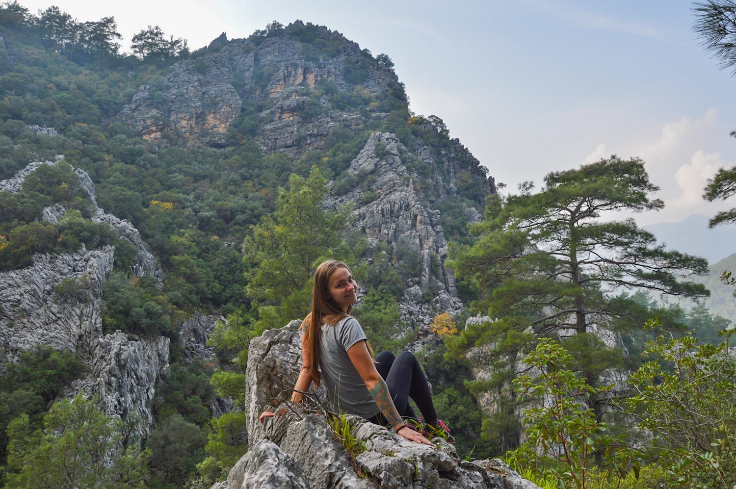 Девушка сидит полубоком в горах