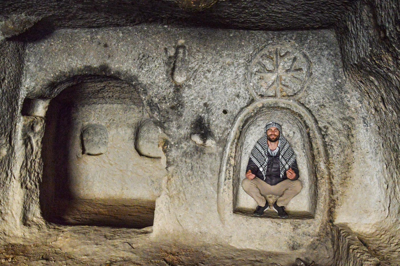 мужчина сидит в арке под византийским крестом