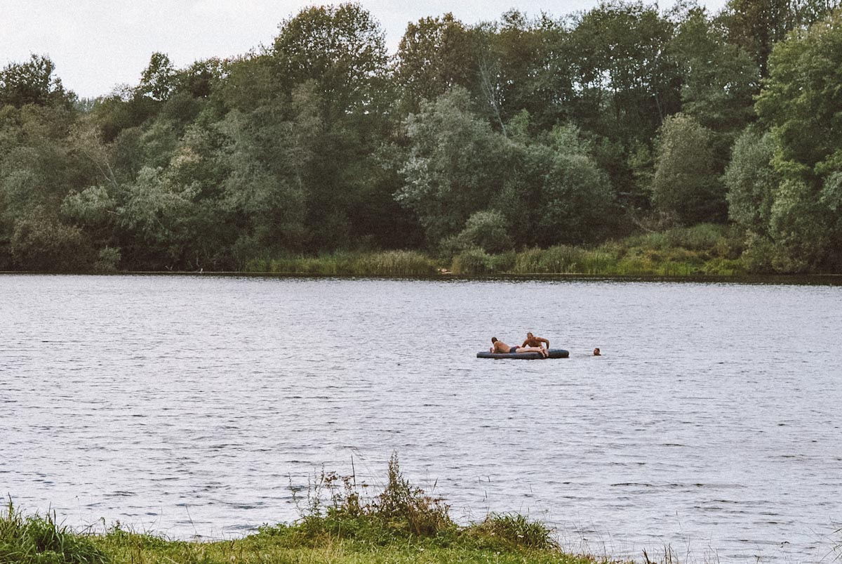 Мужчины плавают в озере на надувном матрасе