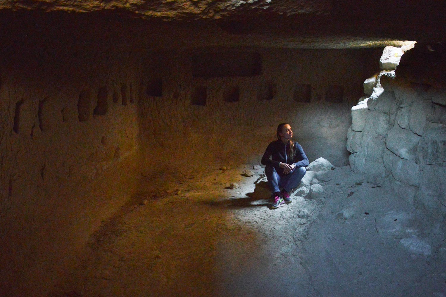 девушка сидит на земле в пещере — поход по долинам Каппадокии