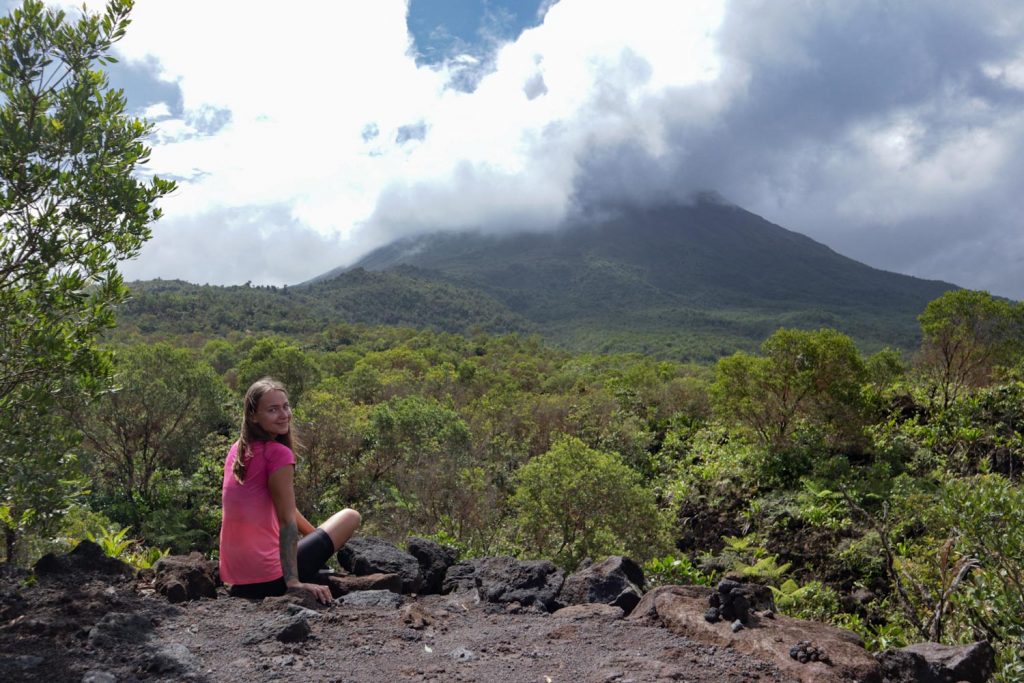 Девушка сидит на фоне вулкана Ареналь