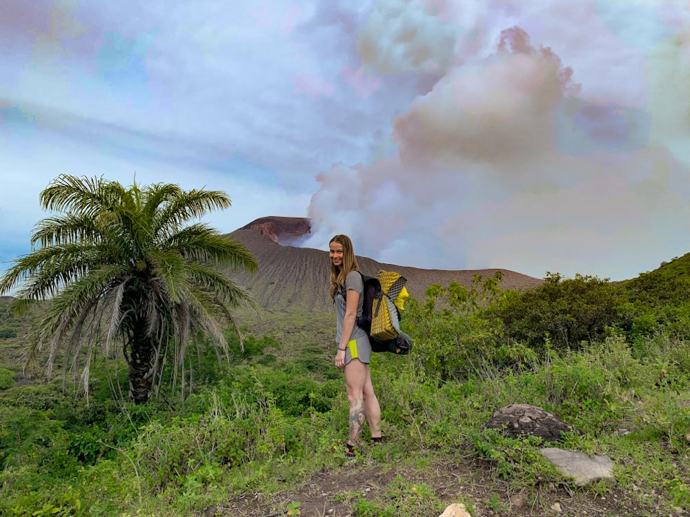 Девушка с рюкзаком на фоне активного вулкана в Никарагуа