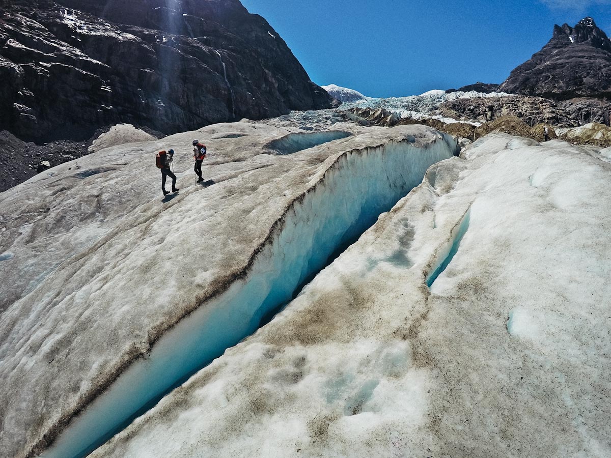 People walking on a Calluqueo glacier along the crevasse / Люди идут по леднику Каюкео вдоль трещины