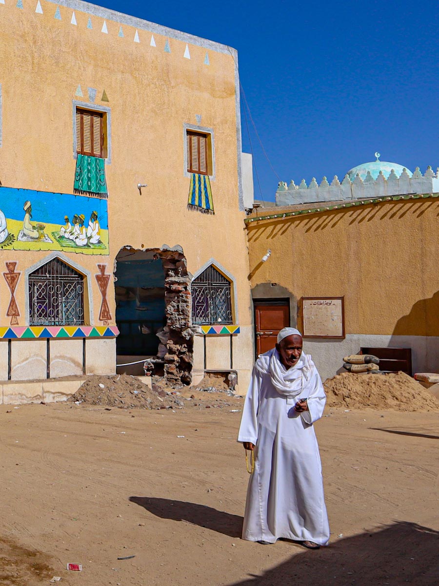 Нубиец в белой одежде у входа в мечеть