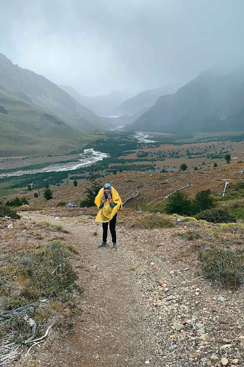 Турист в желтом дождевике на фоне гор