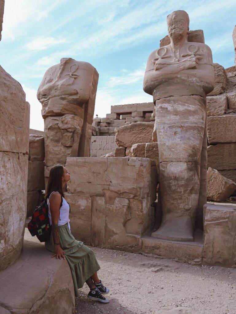 Девушка смотрит на фигуру фараона в Луксоре