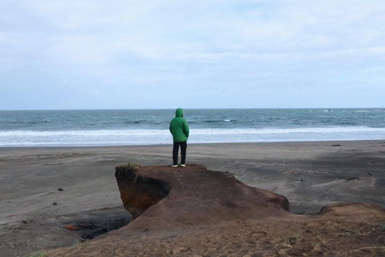 Мужчина смотрит на море на диком пляже