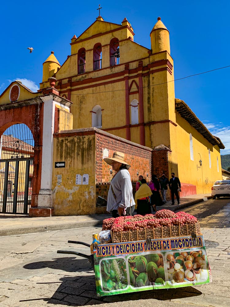 Женщина в шляпу около красно-желтой церкви в Мексике