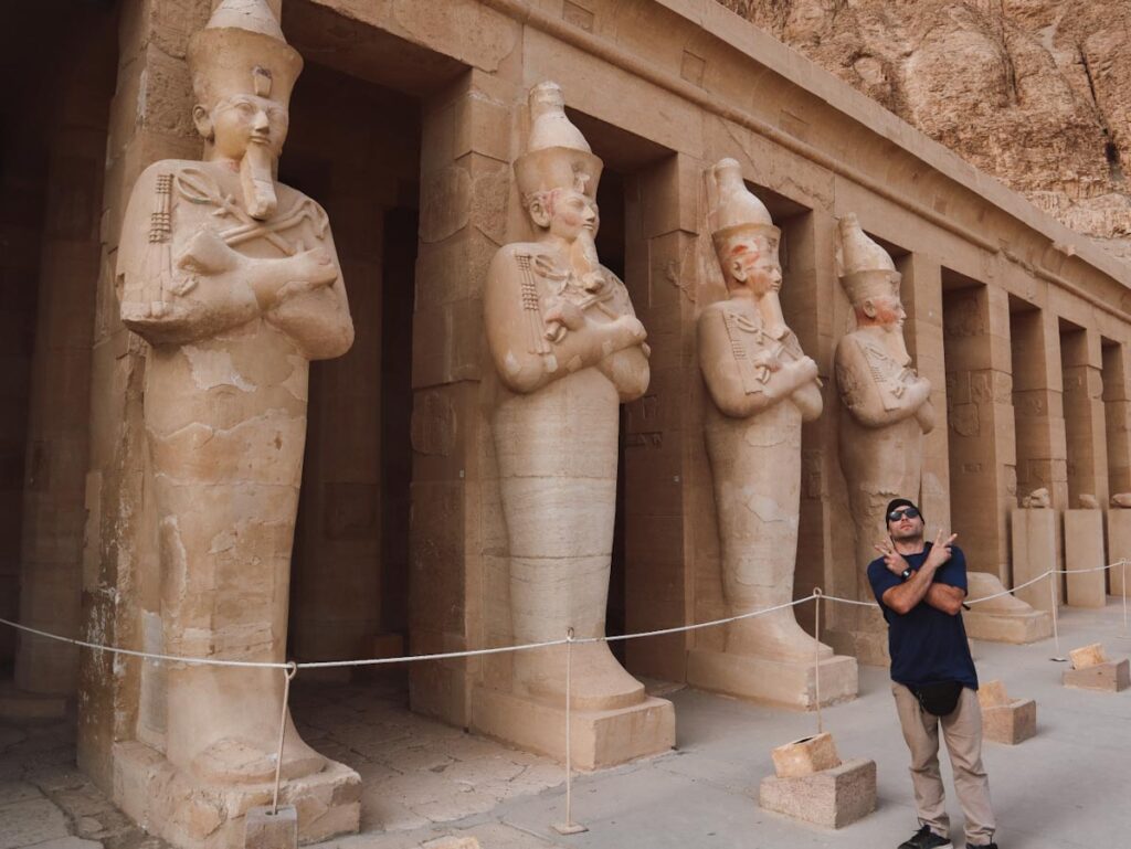 мужчина позирует на фоне статуй фараонов