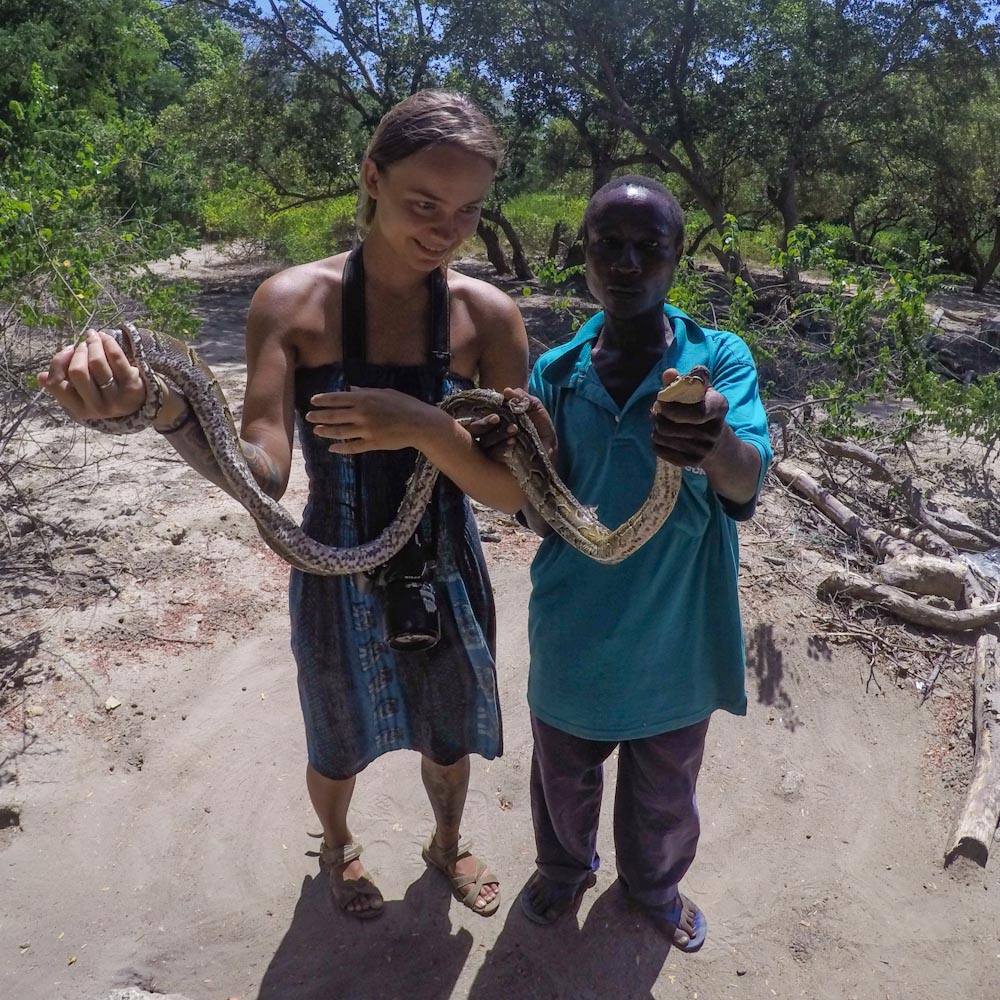 Девушка и кенийский мужчина держат в руках змею 