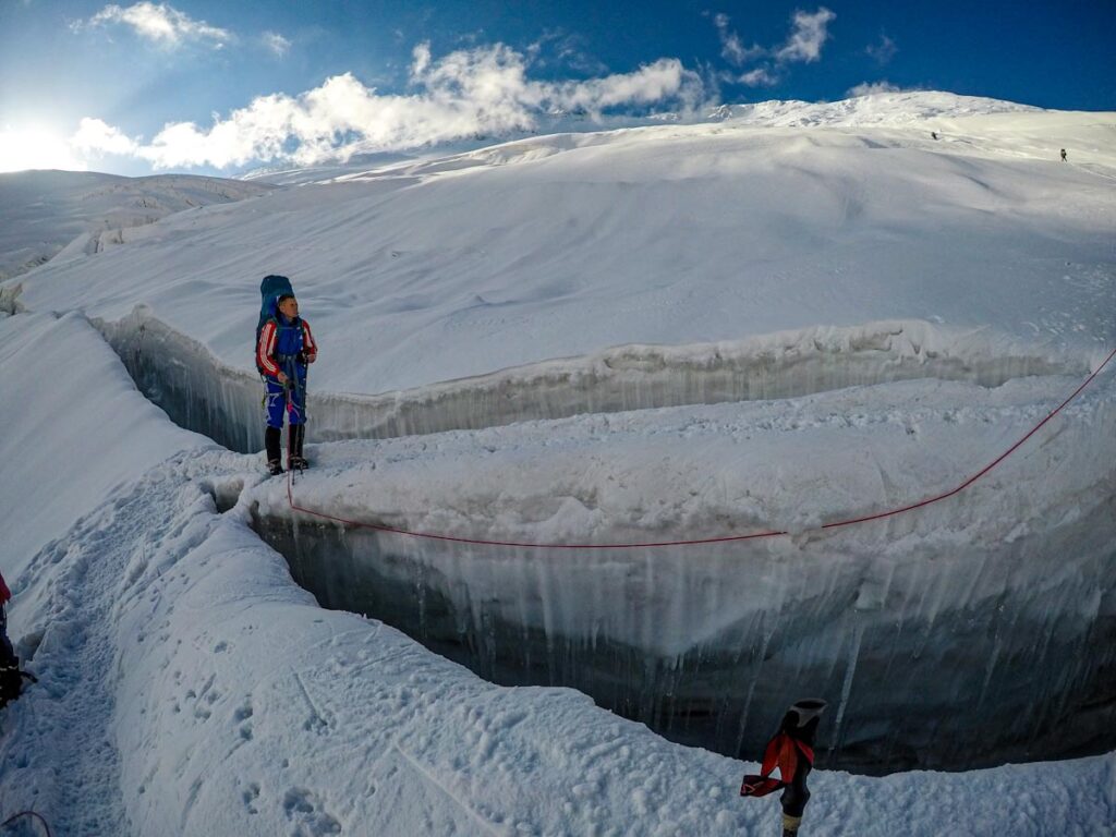 Человек стоит над ледниковой трещиной