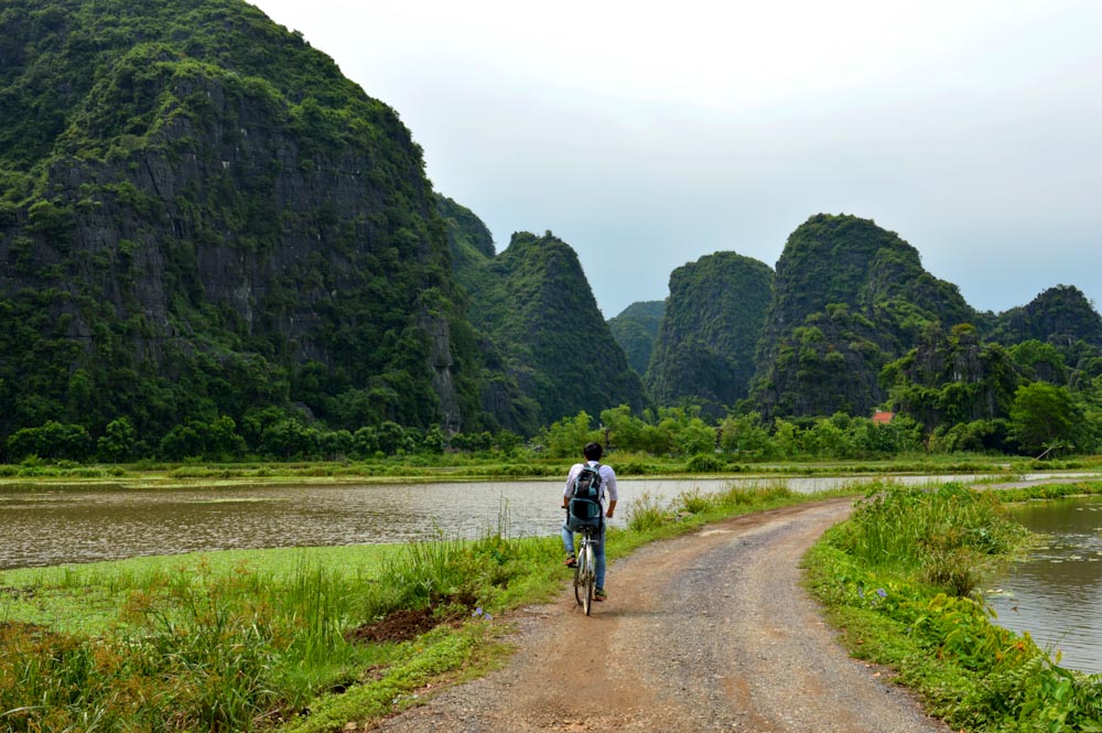 Велосипедист едет по долине Там Кок в провинции Ниньбинь
